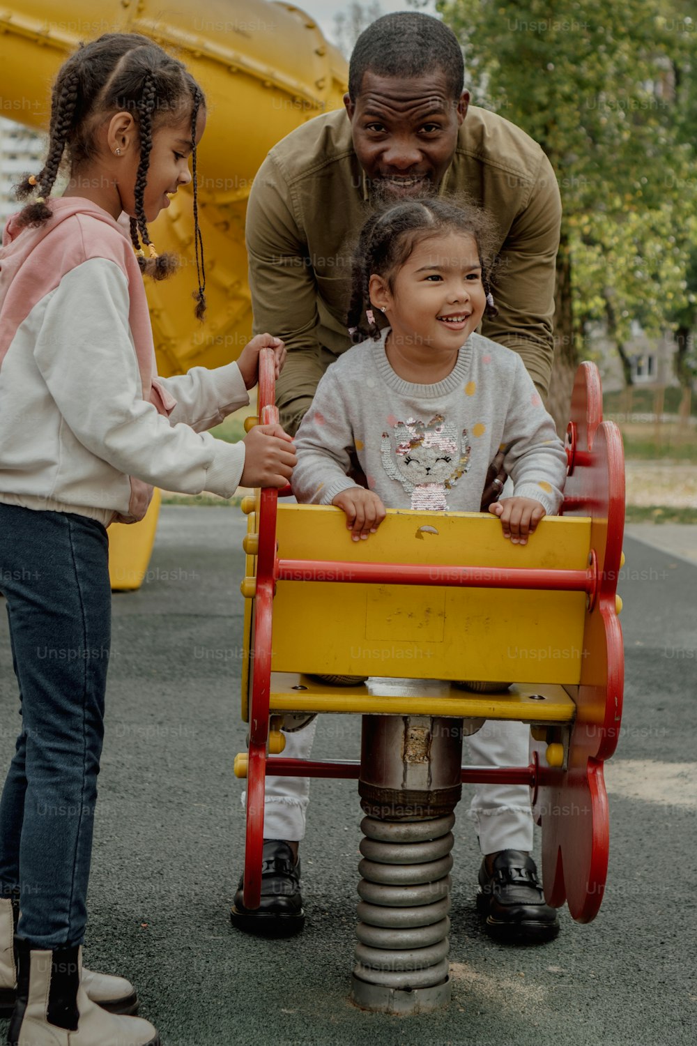 a man and two little girls riding a toy train