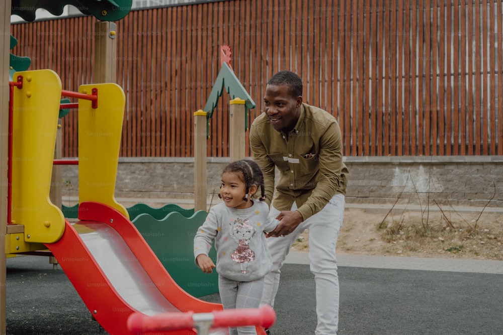 Ein Mann und ein kleines Mädchen spielen auf einem Spielplatz
