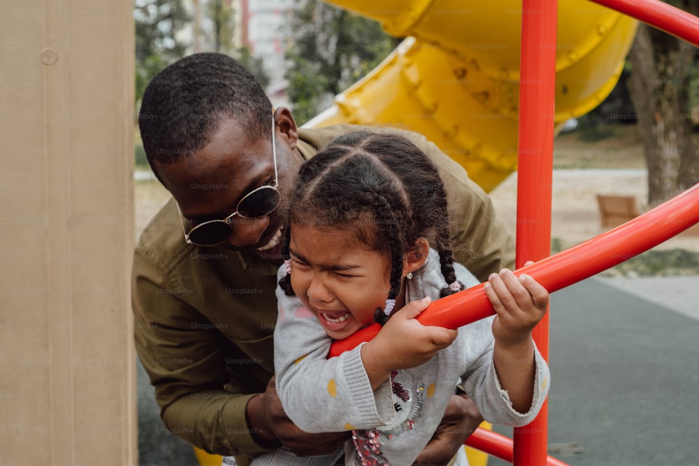 a man and a little girl playing on a playground