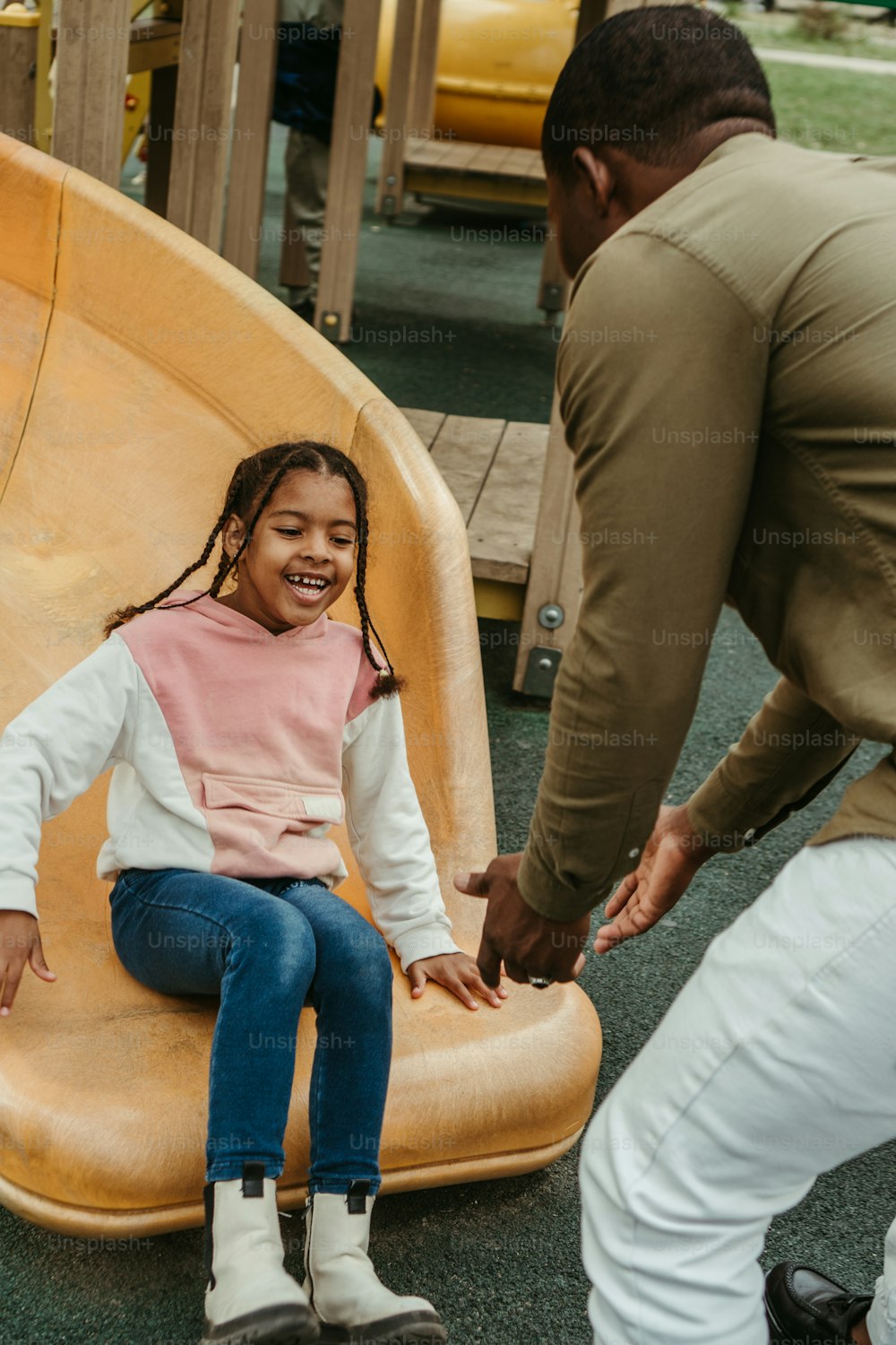 a little girl sitting on a slide in a playground