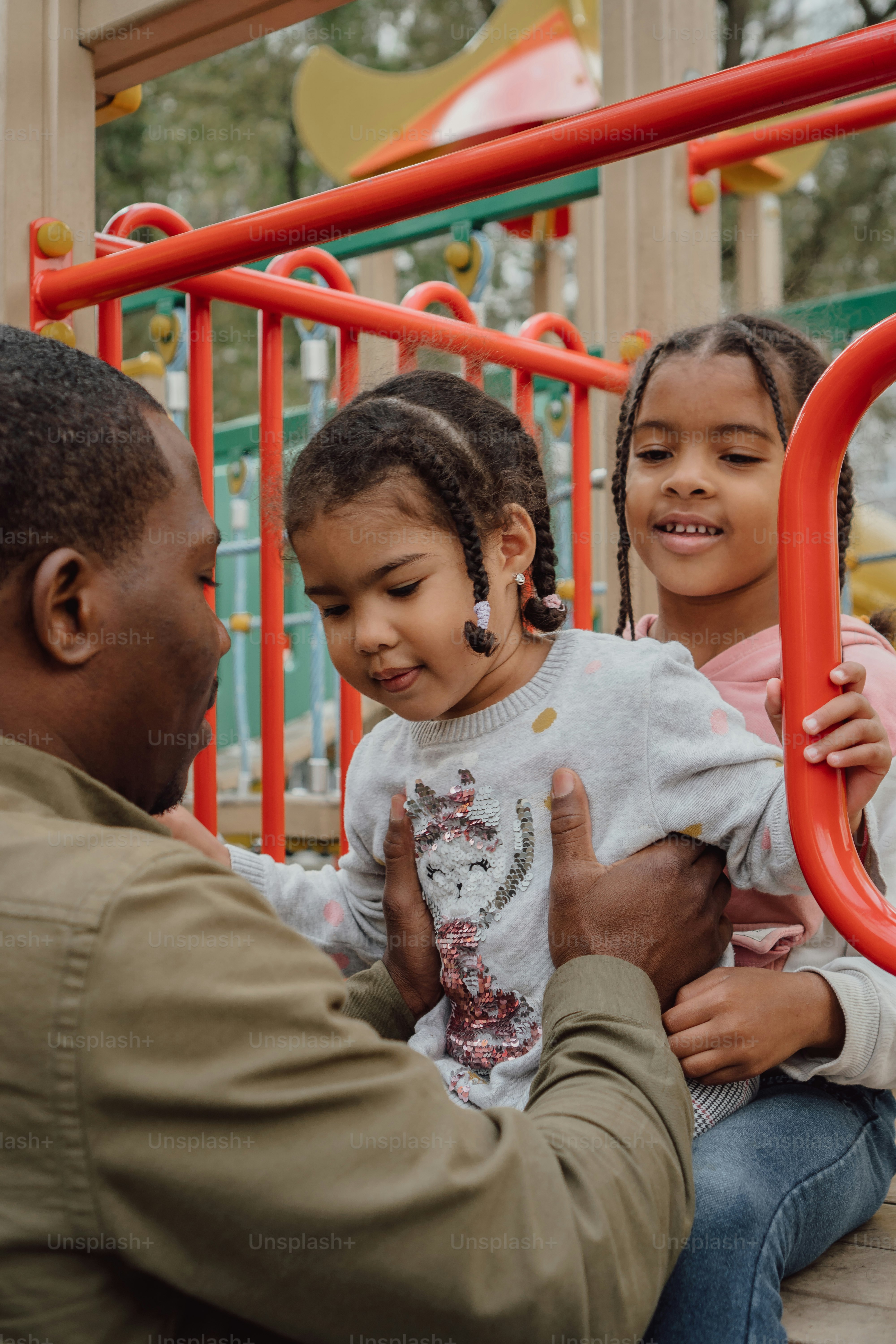 Ein Mann, der ein kleines Mädchen auf einem Spielplatz hält