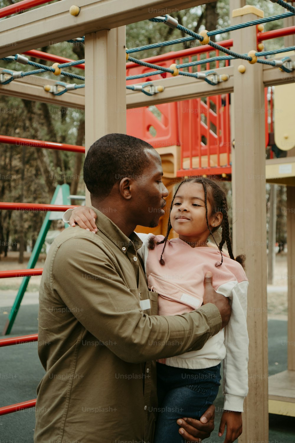 a man holding a little girl in front of a playground