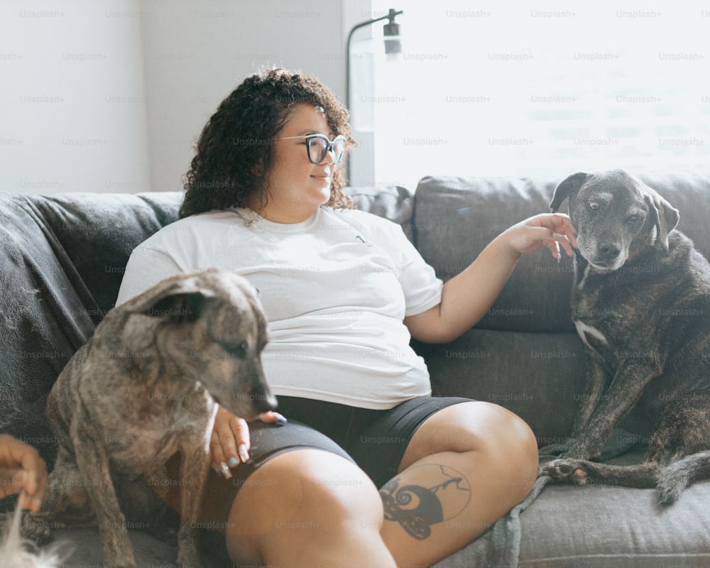 a woman sitting on a couch with two dogs