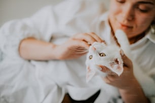 Una donna che tiene un gatto bianco tra le mani