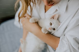 Una mujer sosteniendo un gatito blanco en sus brazos
