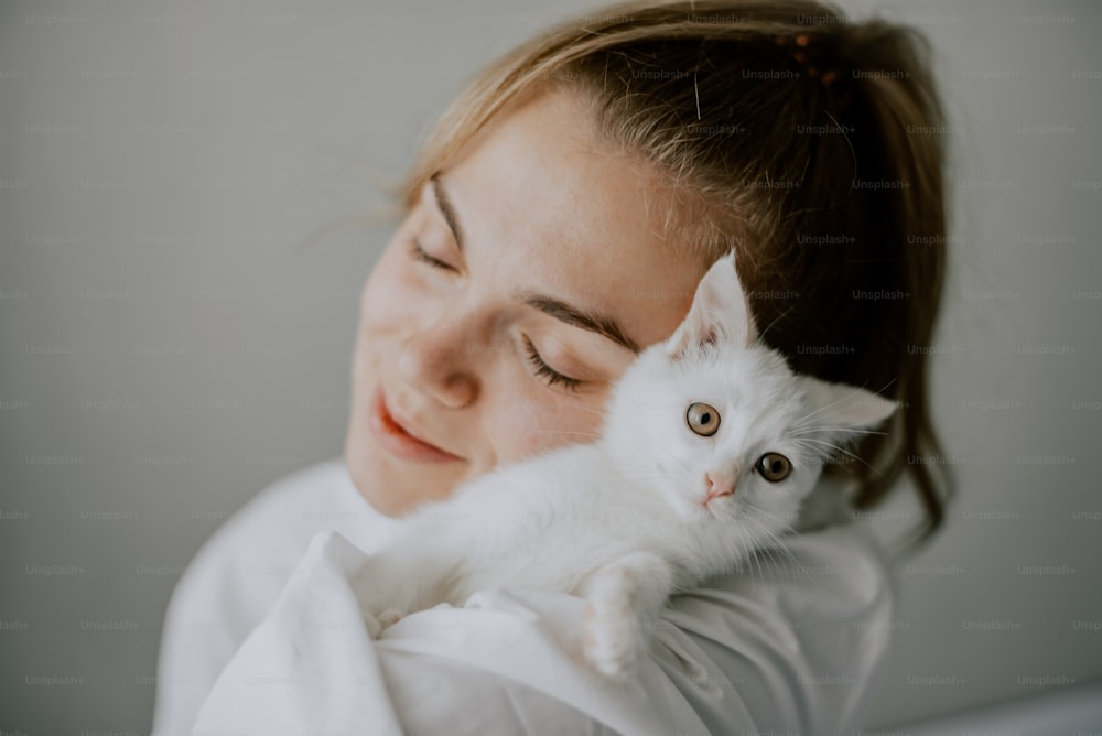 Una donna che tiene un gatto bianco tra le braccia