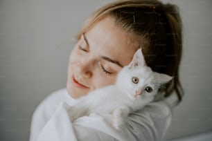 a woman holding a white cat in her arms