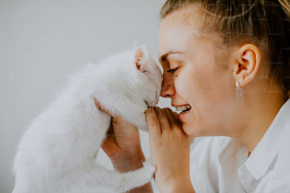 a woman holding a white cat in her hands