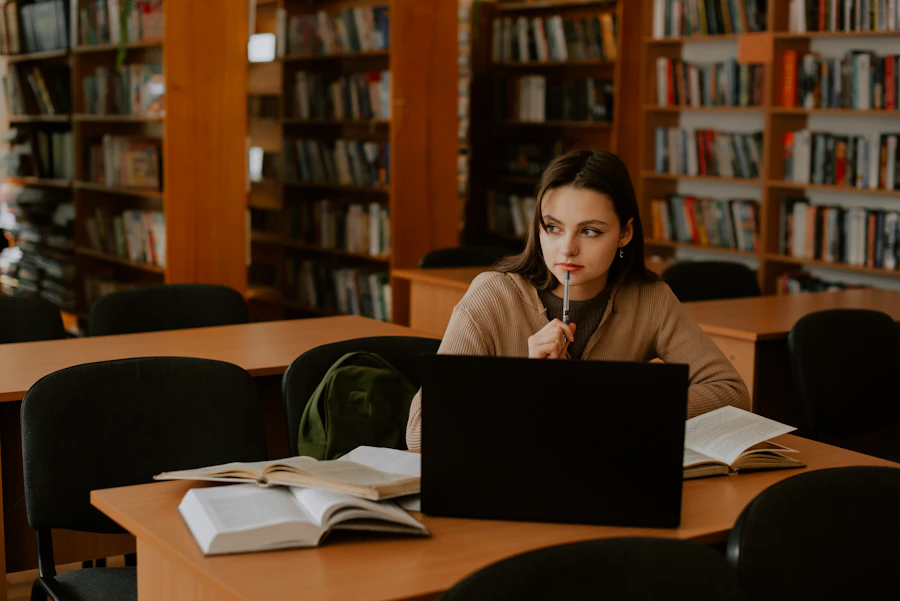 woman in her 60s sitting at home at kitchen table laptop open at night reading intently research warm lamp light comfortable home setting close up face looking at screen with interest