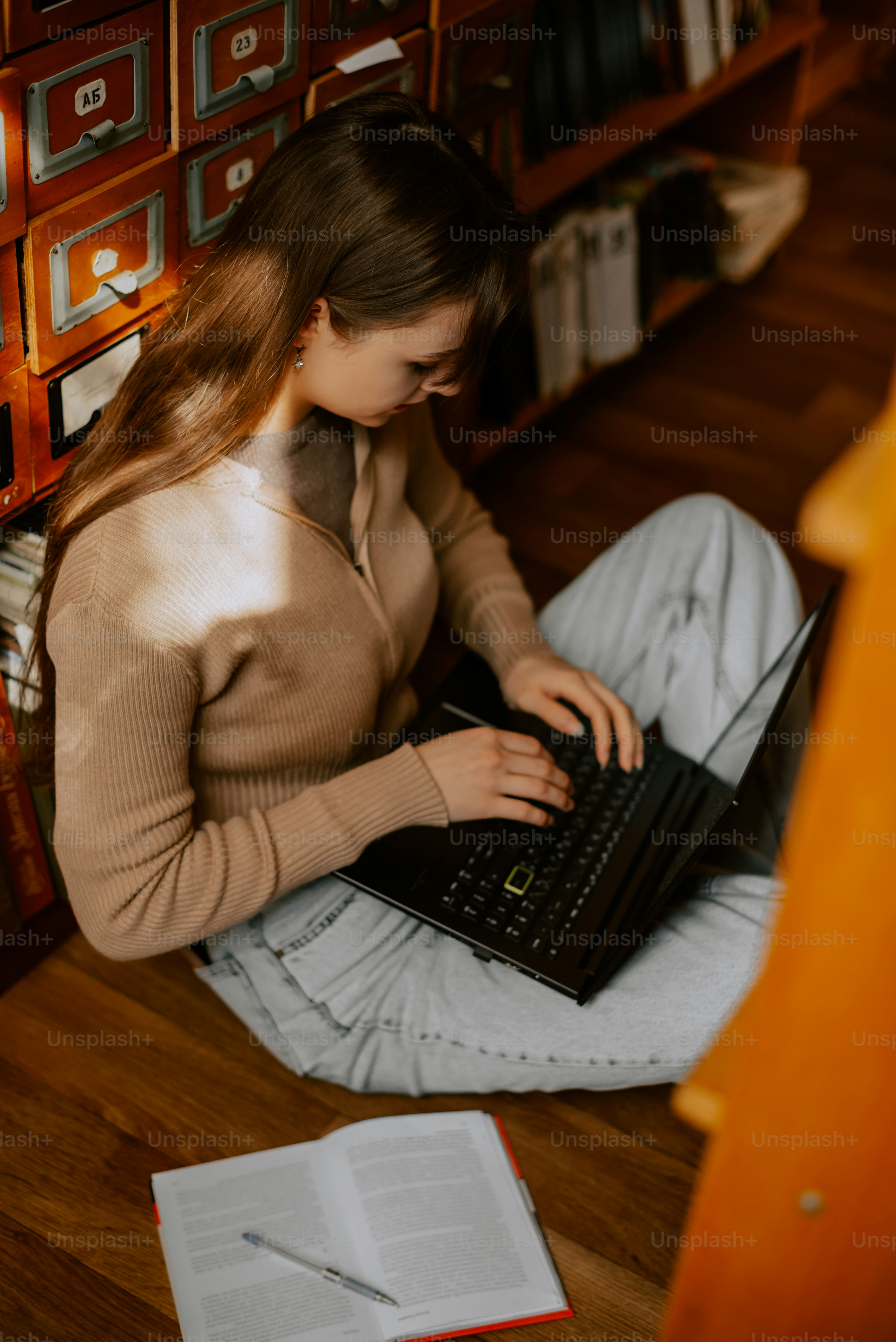 Una mujer sentada en el suelo usando una computadora portátil