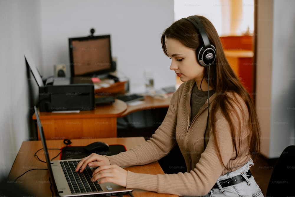 Une femme assise à un bureau avec un ordinateur portable et des écouteurs
