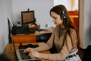 a woman sitting at a desk with a laptop and headphones on