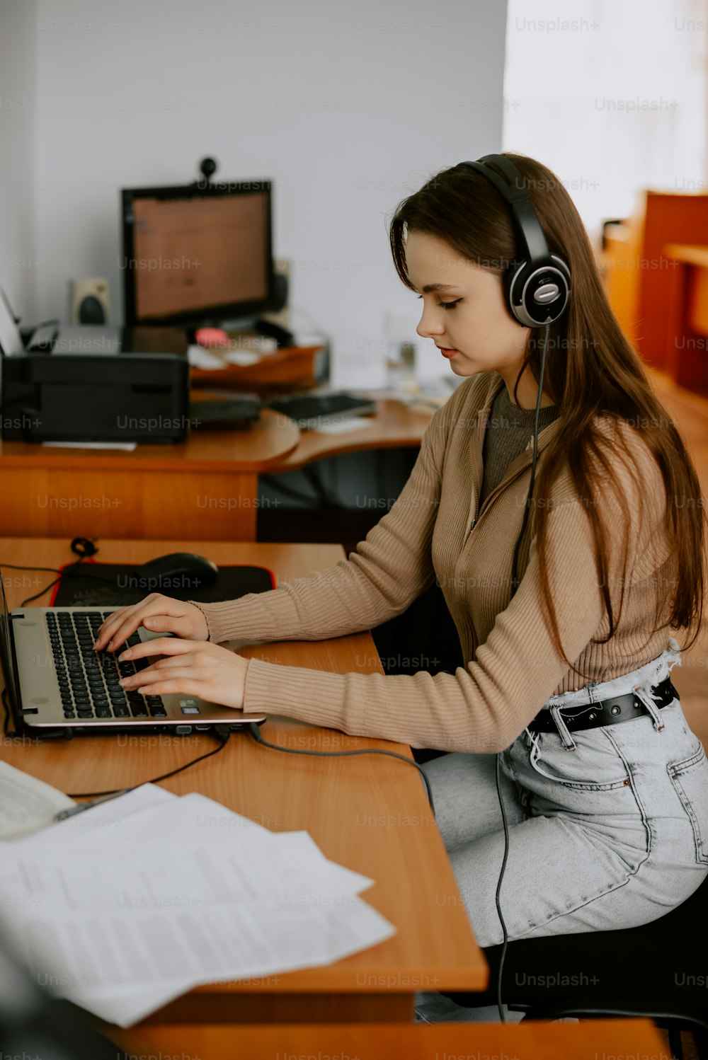 a woman sitting at a desk with a laptop and headphones