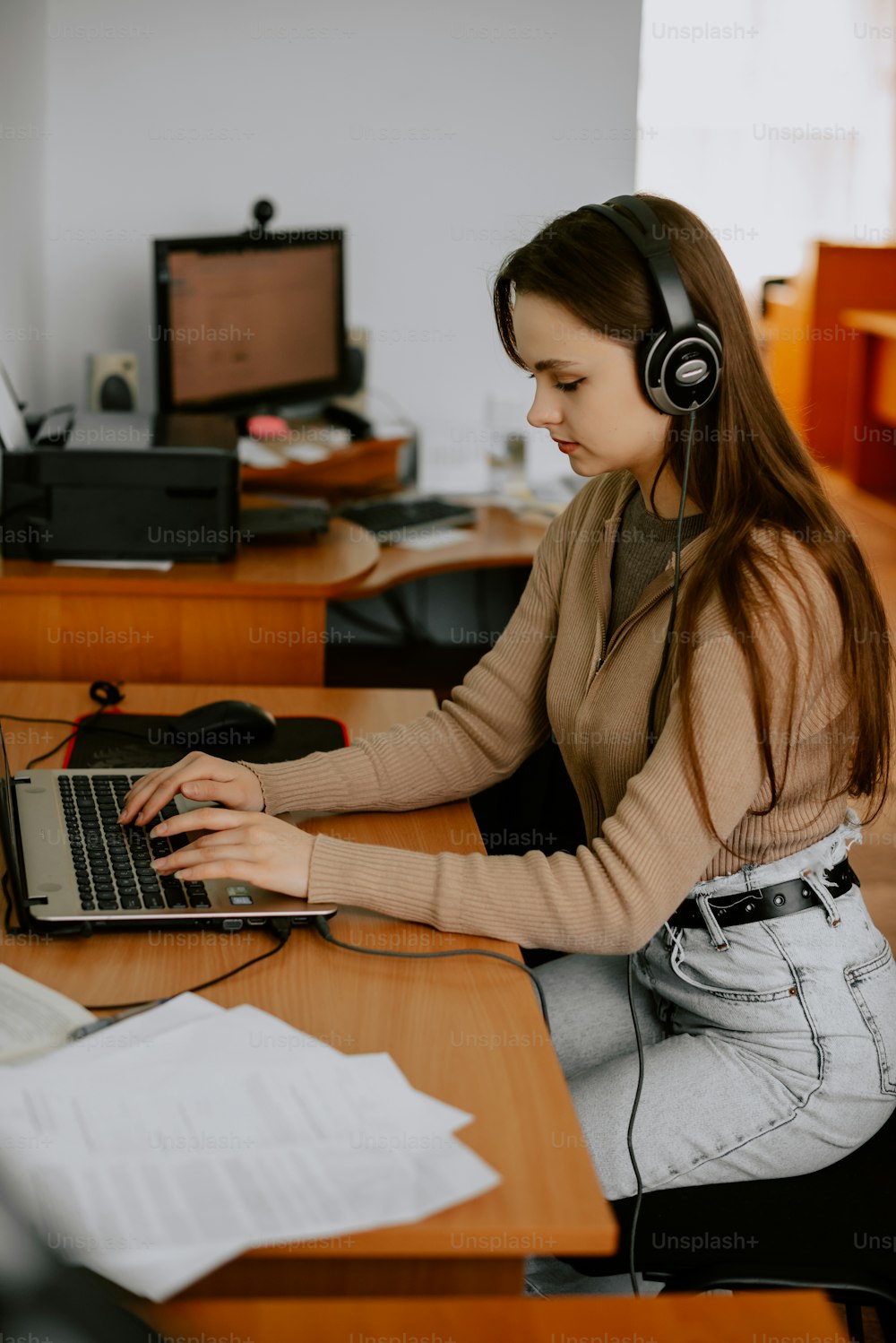 Una mujer sentada en un escritorio con una computadora portátil y auriculares