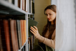 Una mujer está mirando un libro en una biblioteca