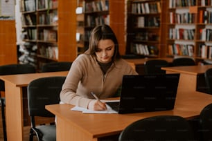 a woman sitting at a table in front of a laptop computer