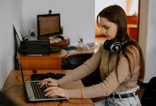 Una mujer sentada frente a una computadora portátil con auriculares
