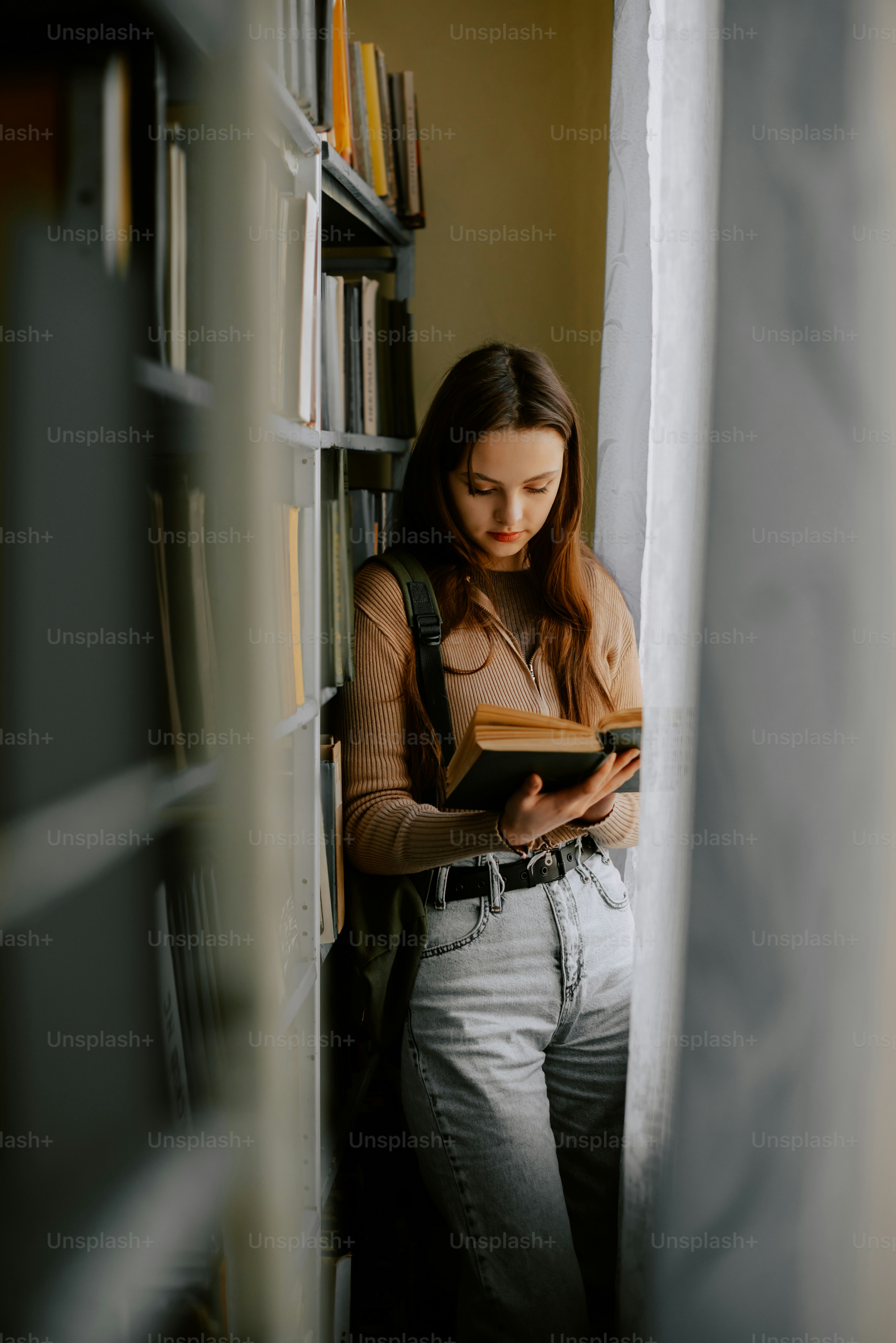 Una mujer está leyendo un libro en una biblioteca