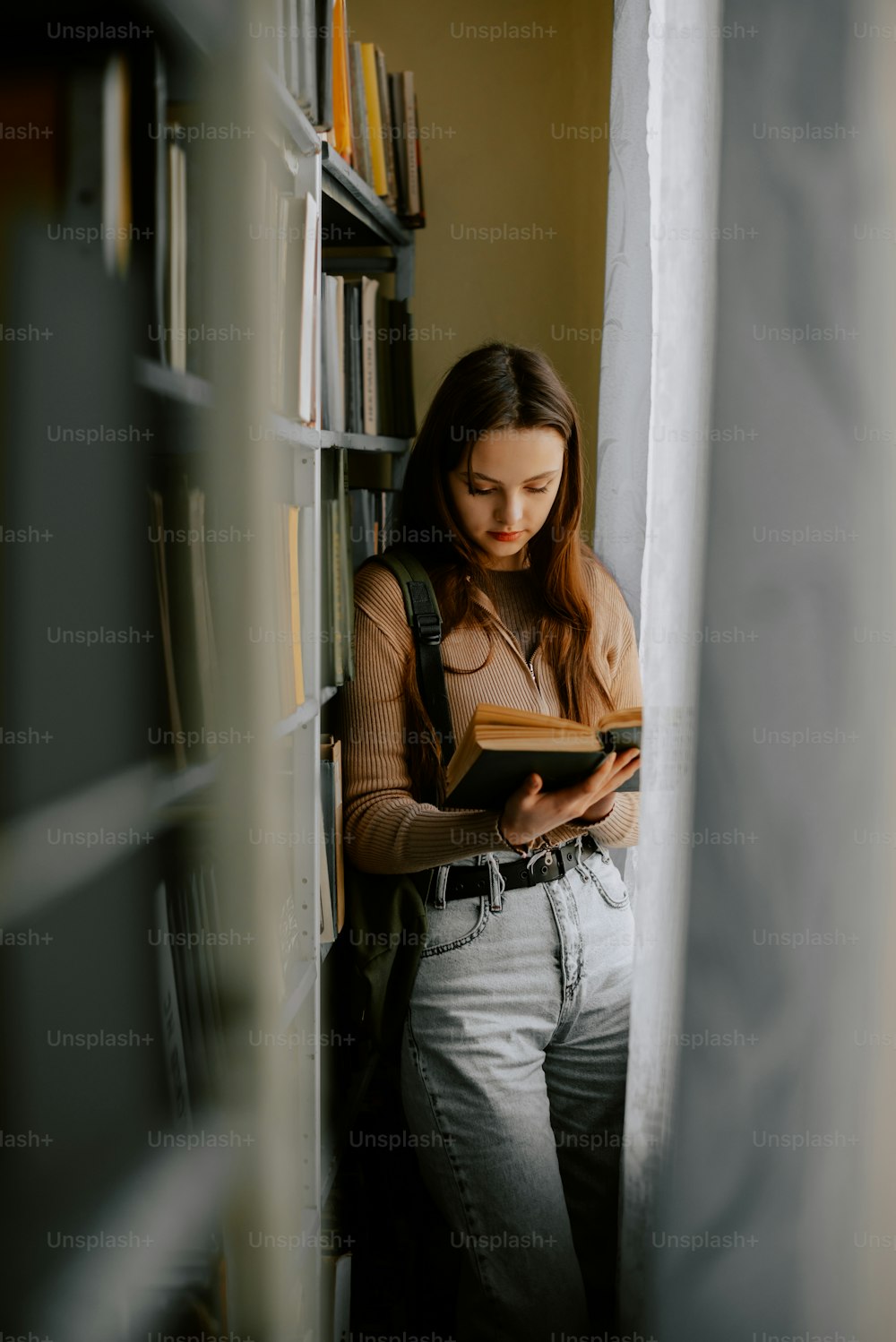 a woman is reading a book in a library