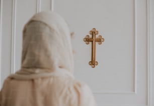 Eine Frau in einem weißen Gewand steht vor einem Kreuz
