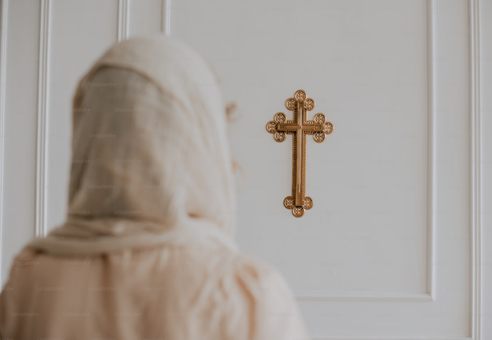 uma mulher com um manto branco em pé na frente de uma cruz