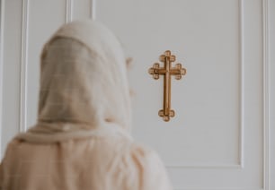 a woman in a white robe standing in front of a cross