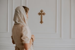 a woman standing in front of a wall with a cross on it