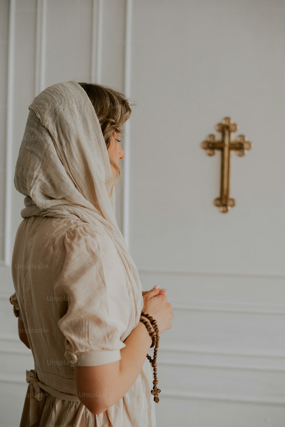 Eine Frau in einem weißen Kleid, die vor einem Kreuz steht