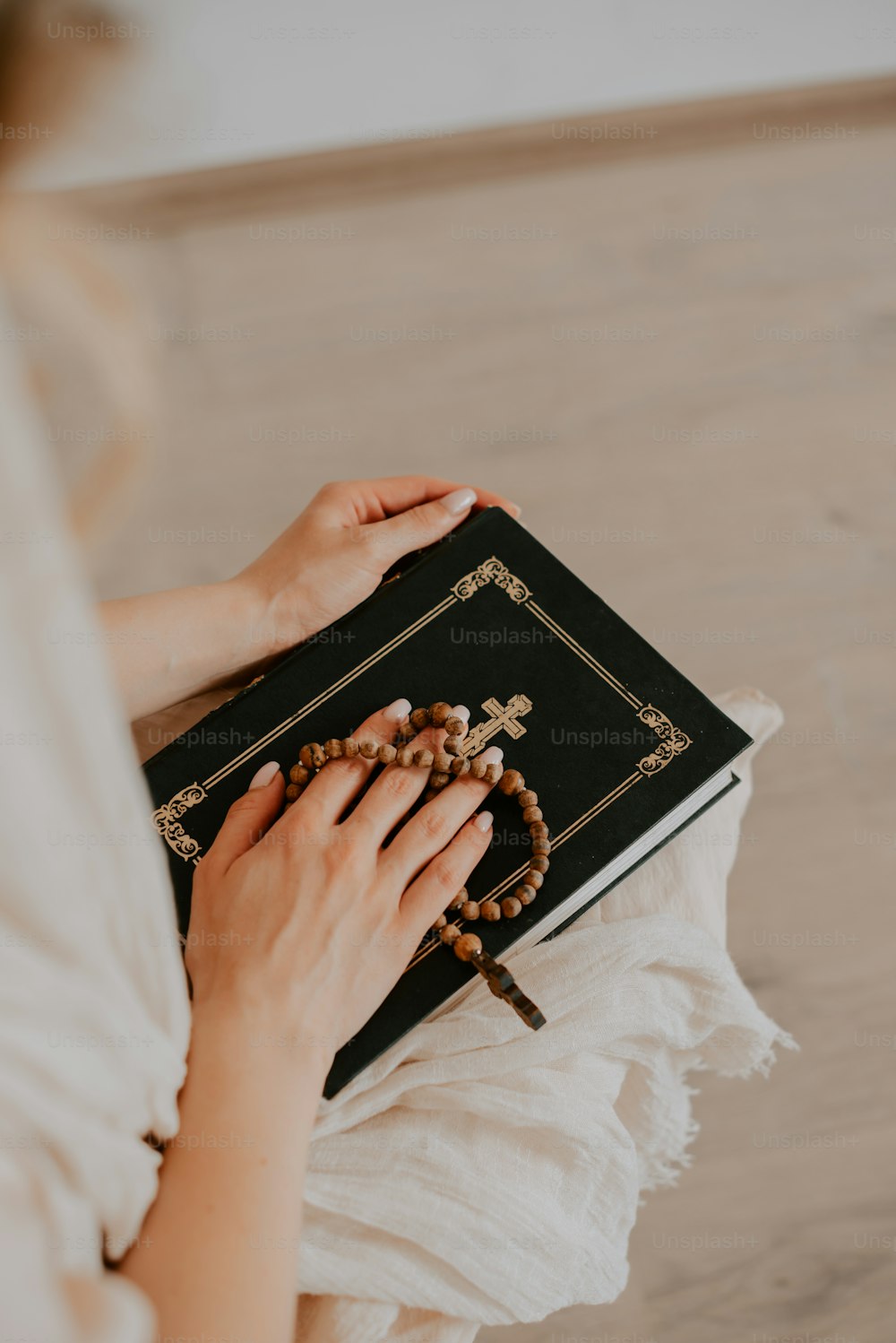 a woman is holding a rosary and a book