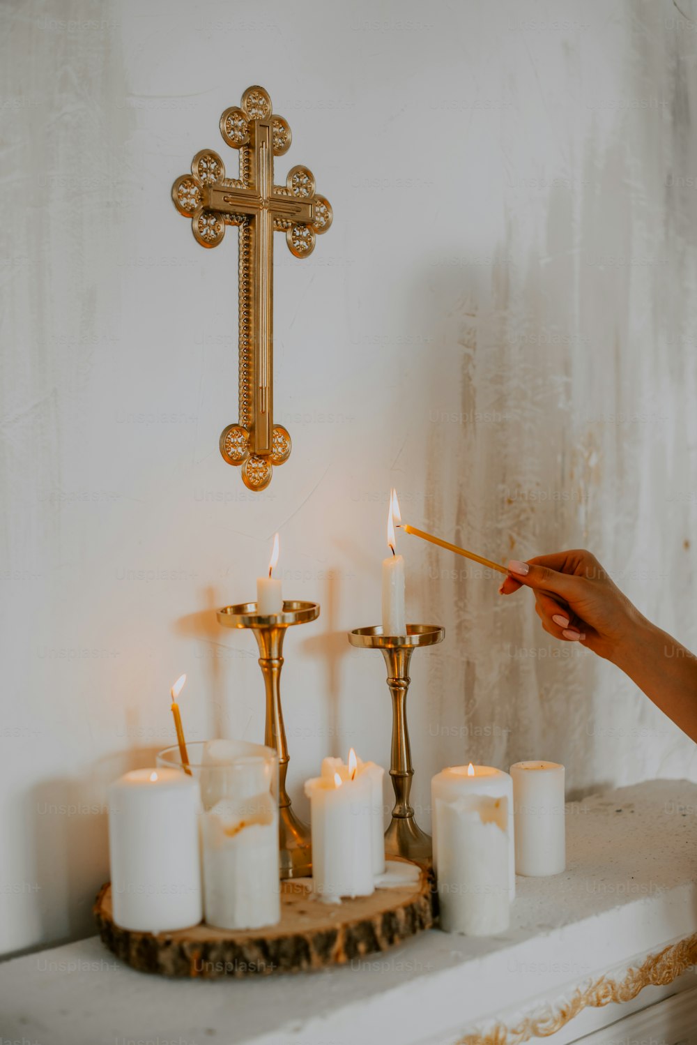 Una persona encendiendo velas frente a una cruz