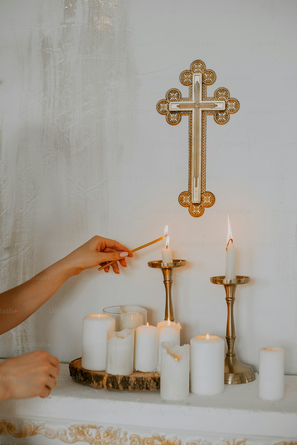 eine Person, die Kerzen vor einem Kreuz anzündet
