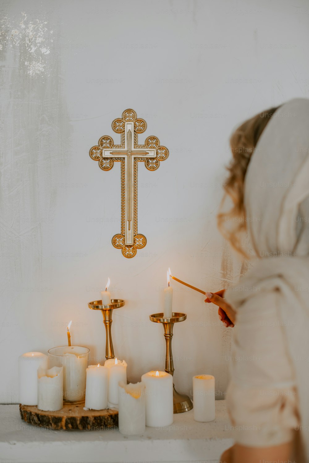a woman standing in front of a cross and candles