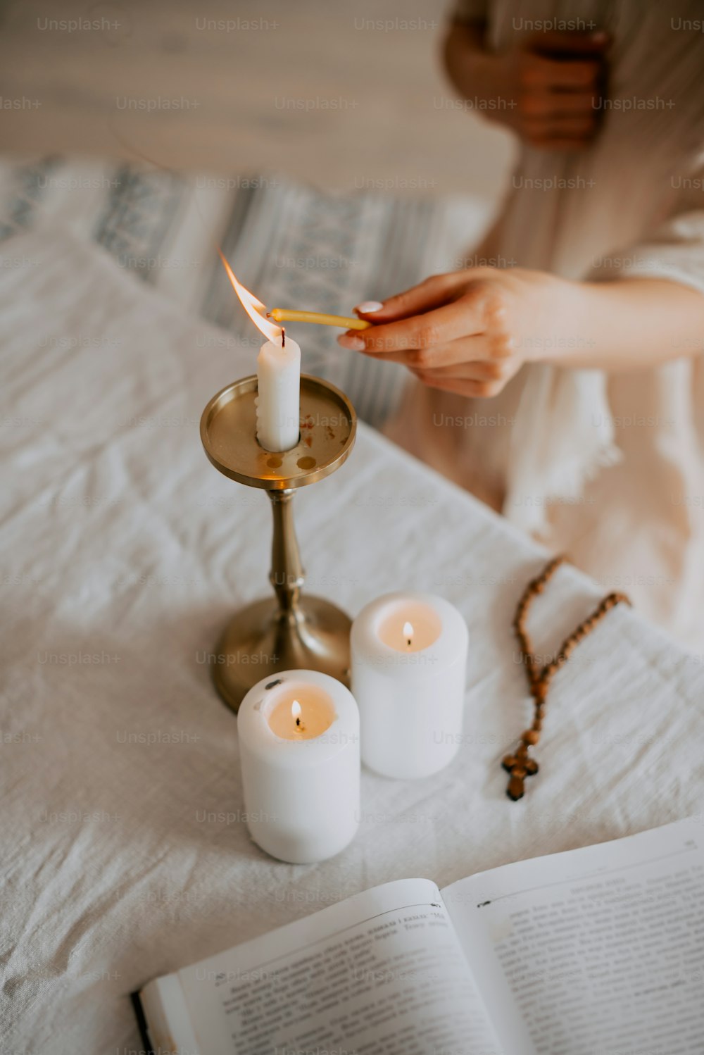 a person lighting a candle on a bed