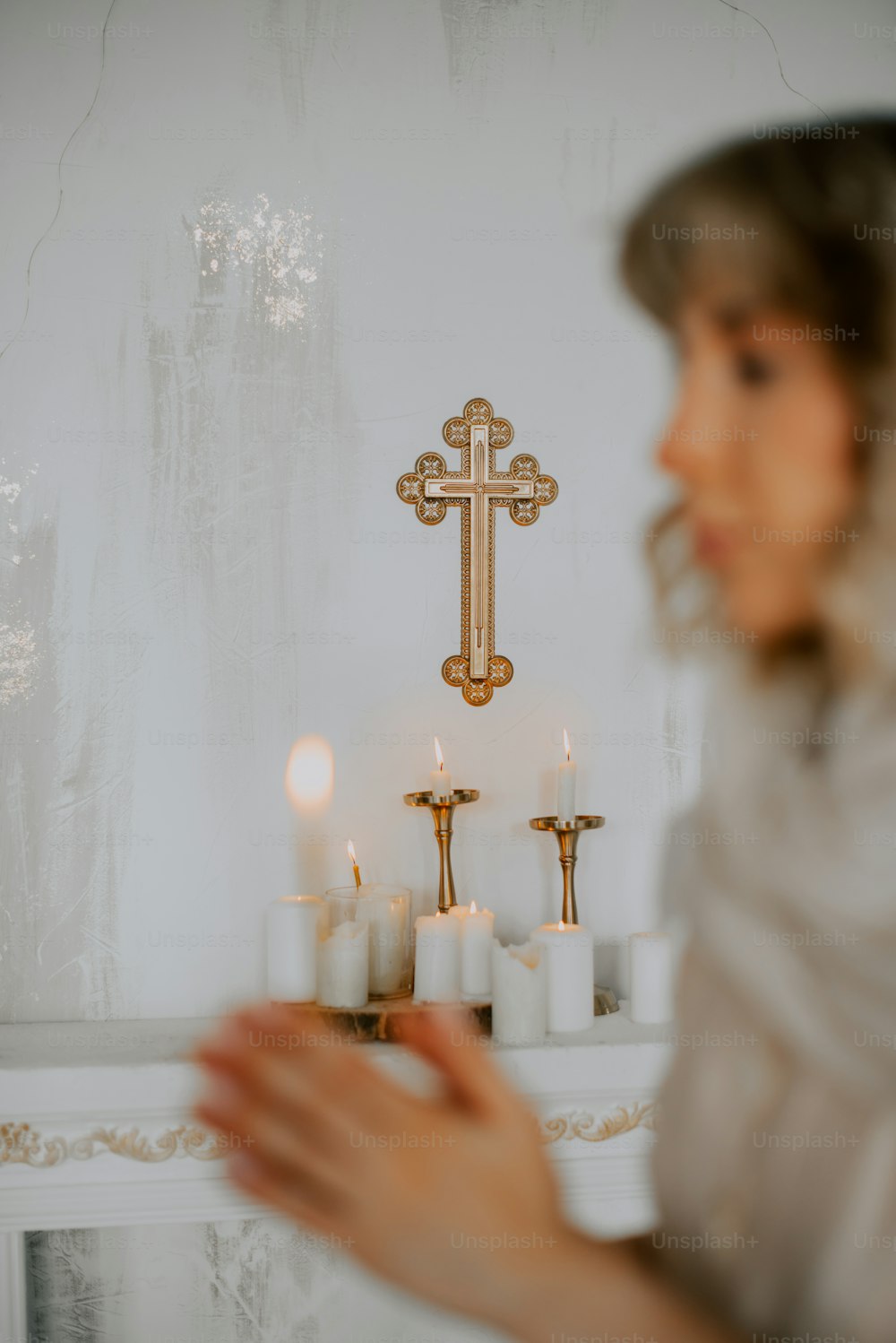 a woman holding a lit candle in front of a cross