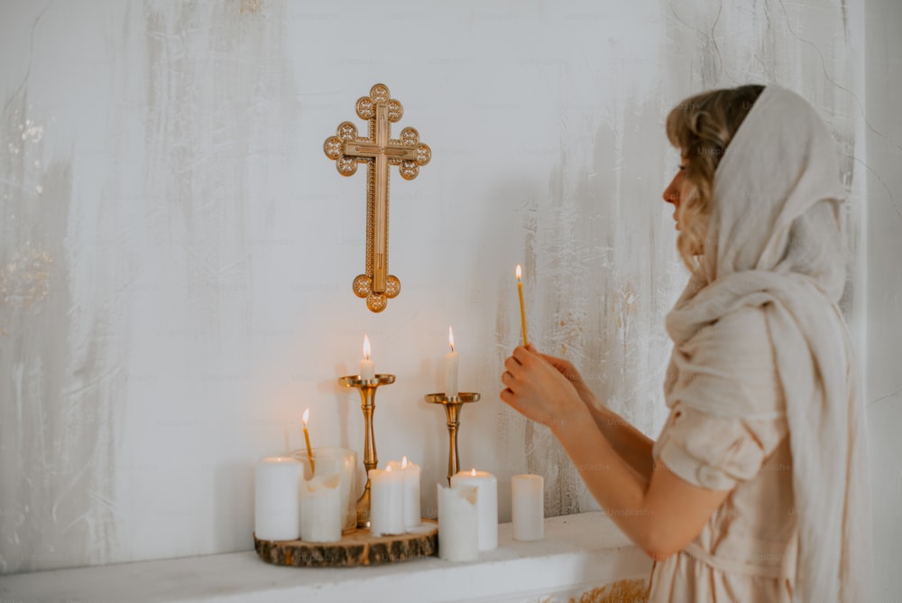 a woman holding a candle in front of a cross