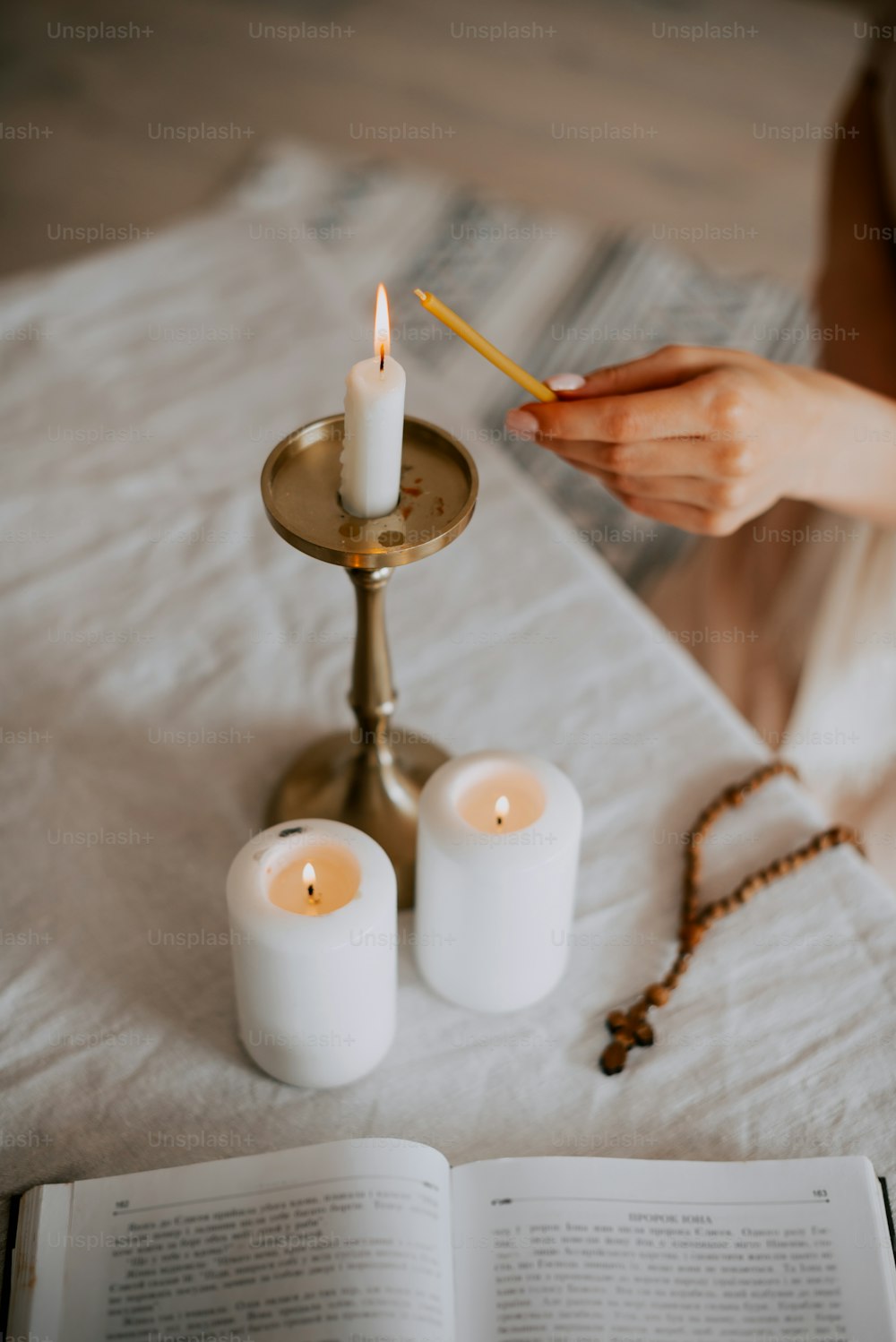 una donna seduta a un tavolo con una candela e un libro