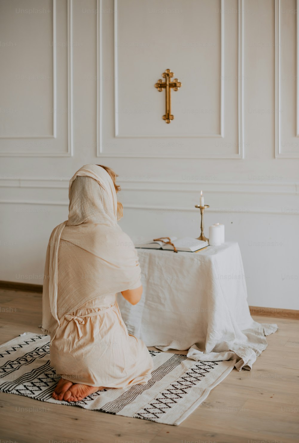 a woman sitting on a rug in front of a table