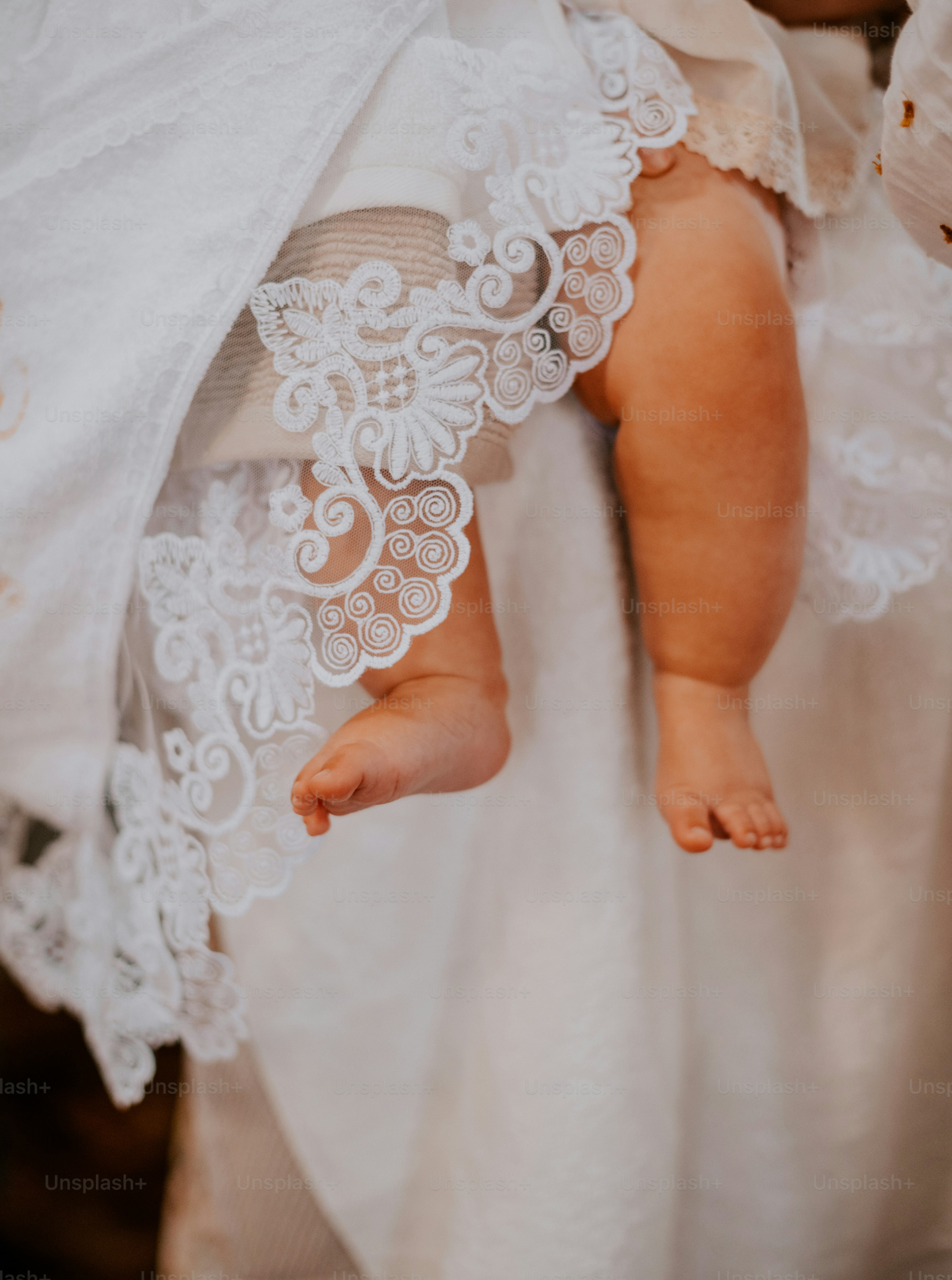 a baby in a white dress holding a white blanket