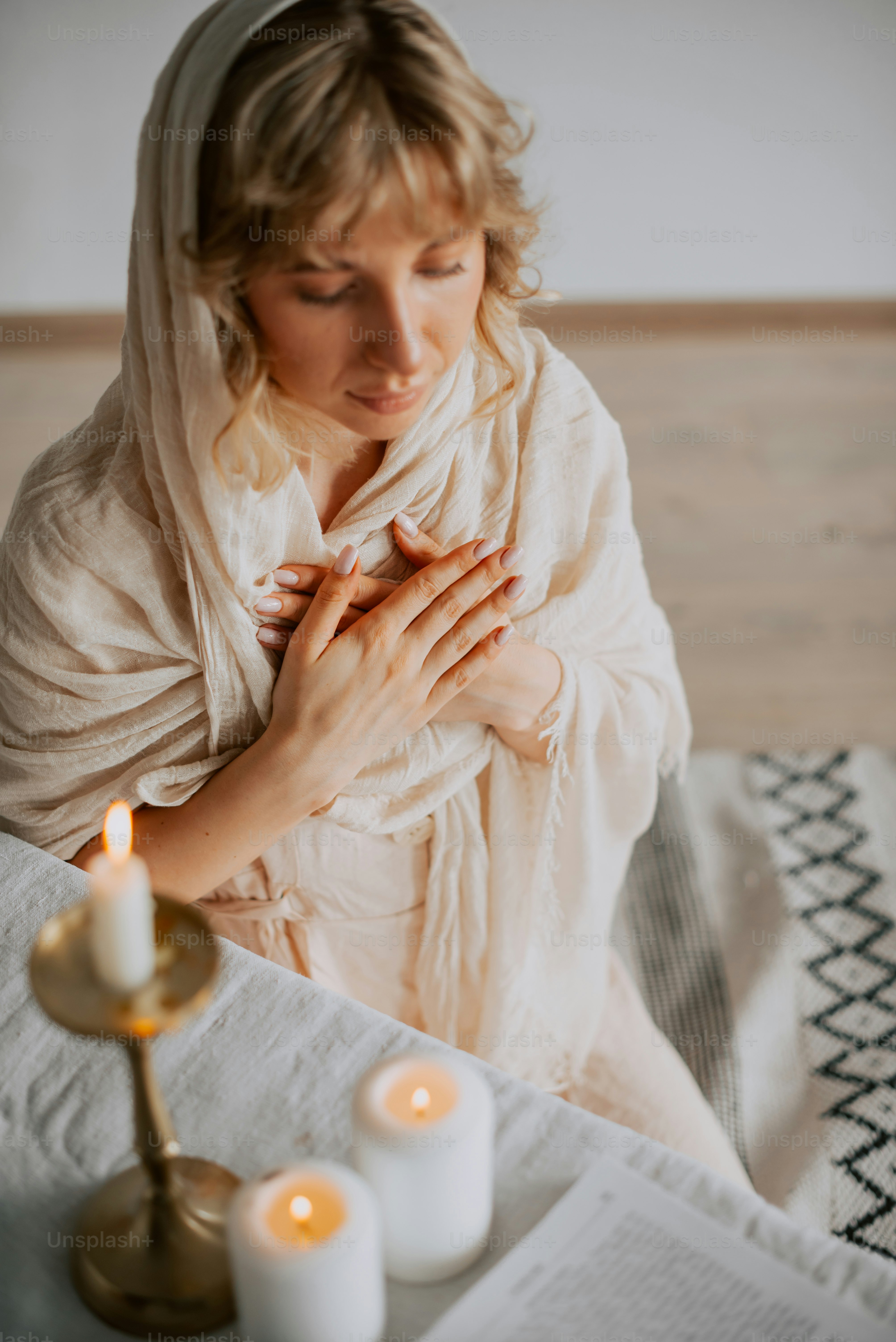 a woman sitting on a bed holding her hands together