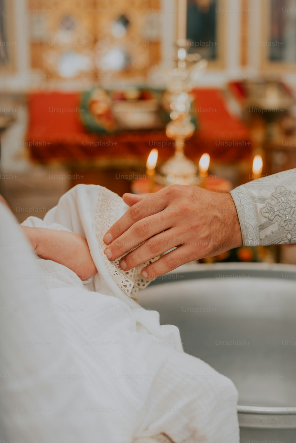 Ein Baby wird von einem Priester gehalten