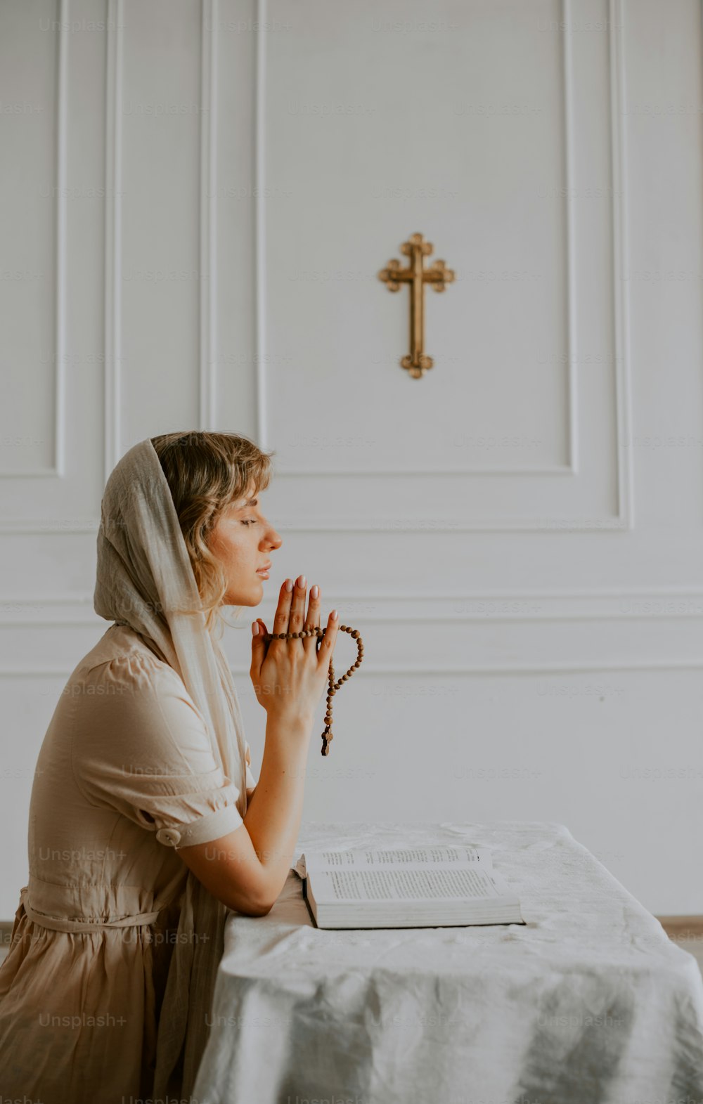 Eine Frau, die an einem Tisch vor einem Kreuz sitzt