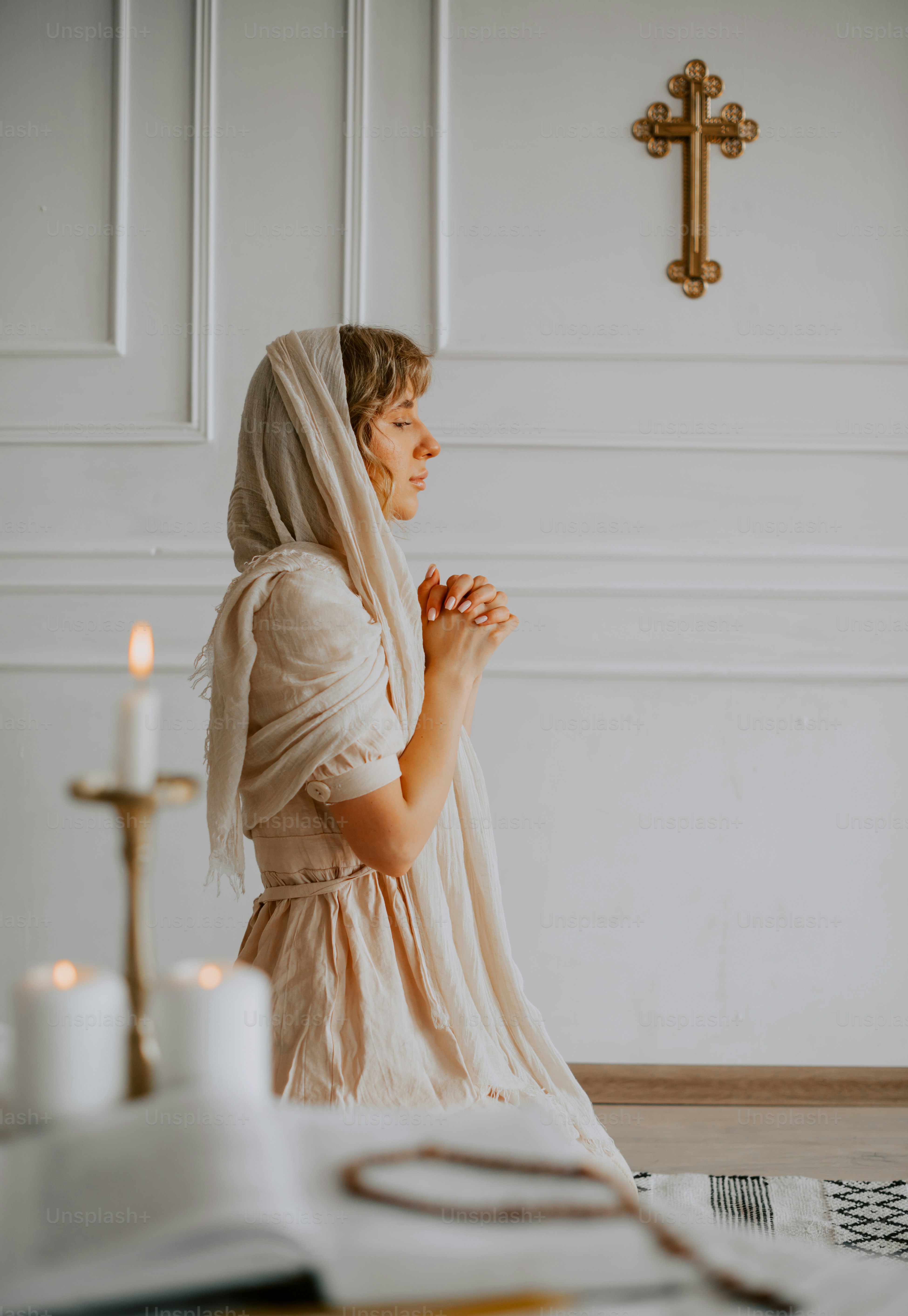 a woman sitting on the floor in front of a cross