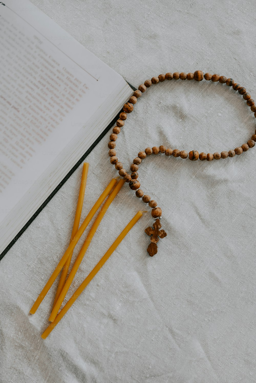 a rosary, two yellow pencils, and a book on a table