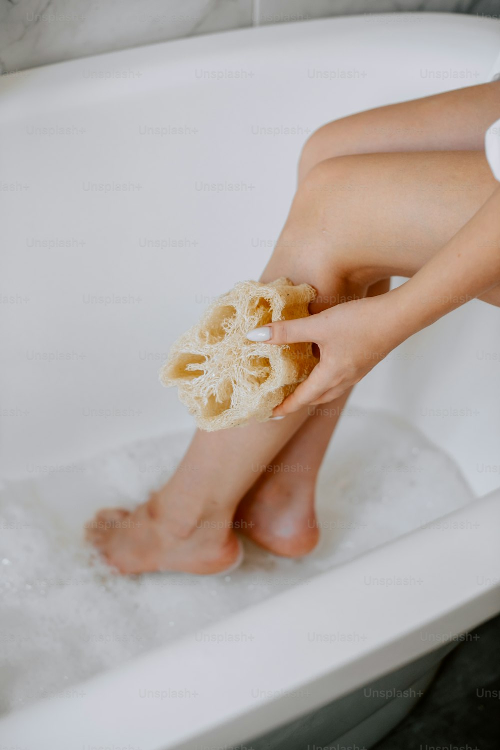 una persona seduta in una vasca da bagno con i piedi nell'acqua