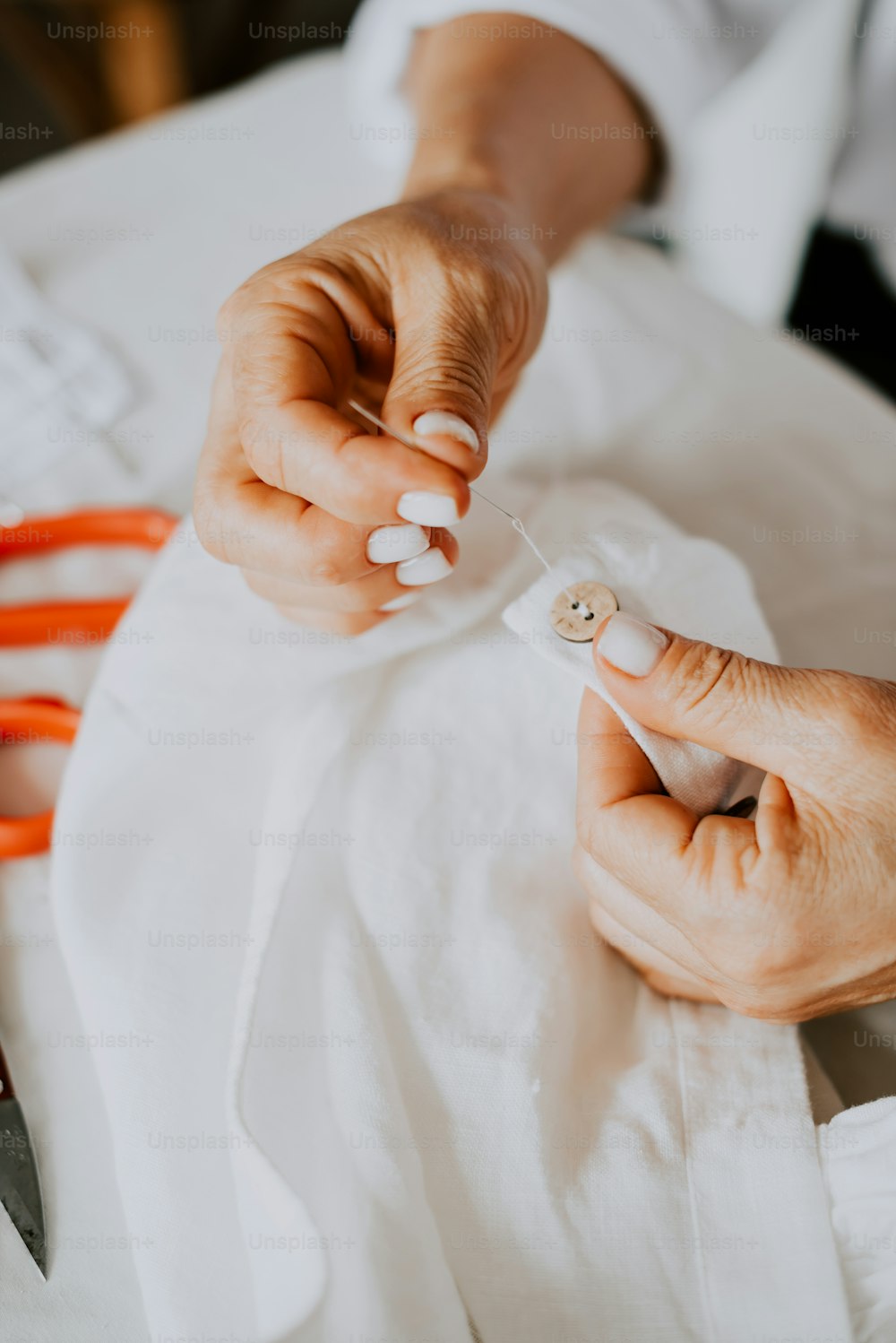 a person is sewing on a white cloth