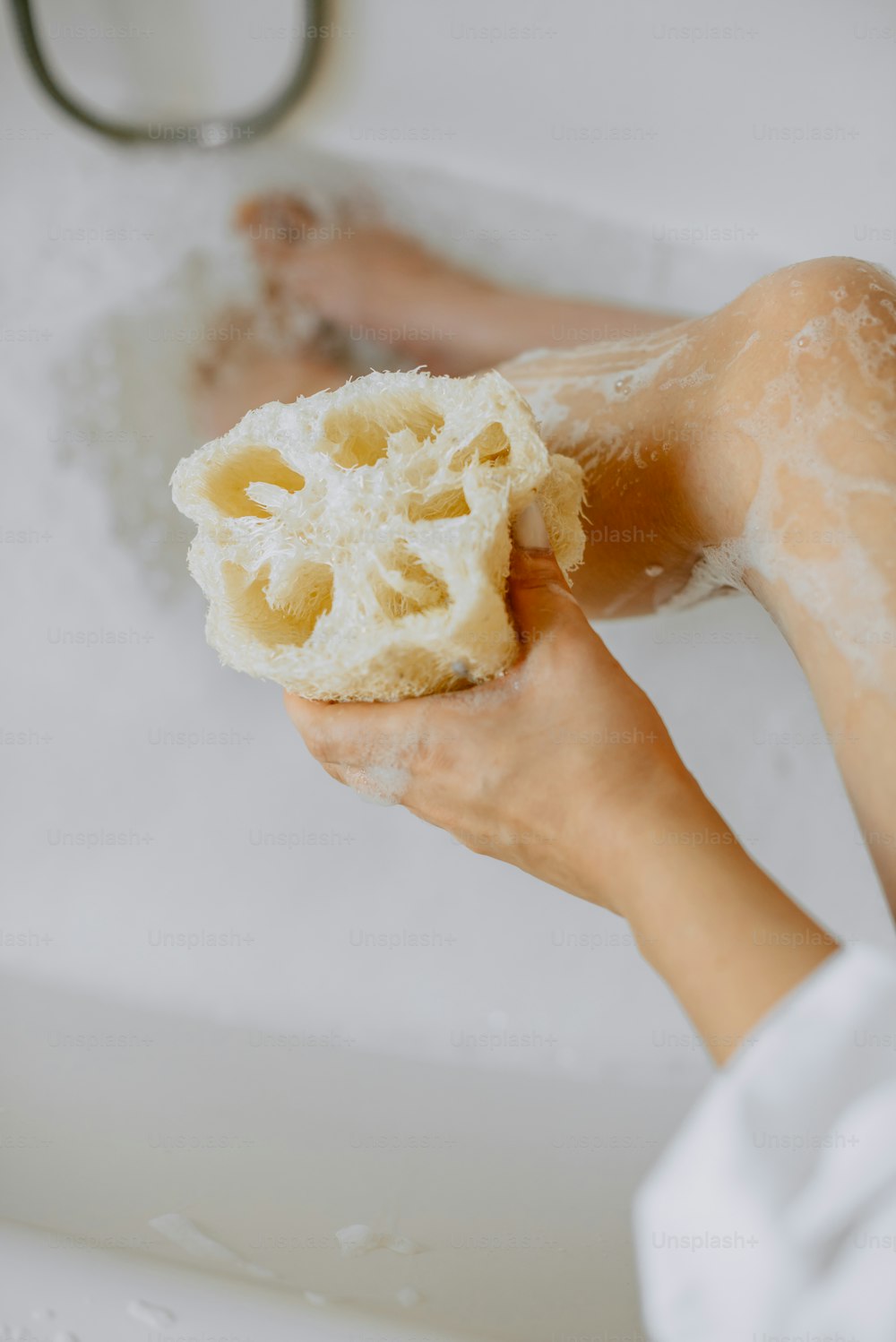 a person holding a sponge in a bathtub