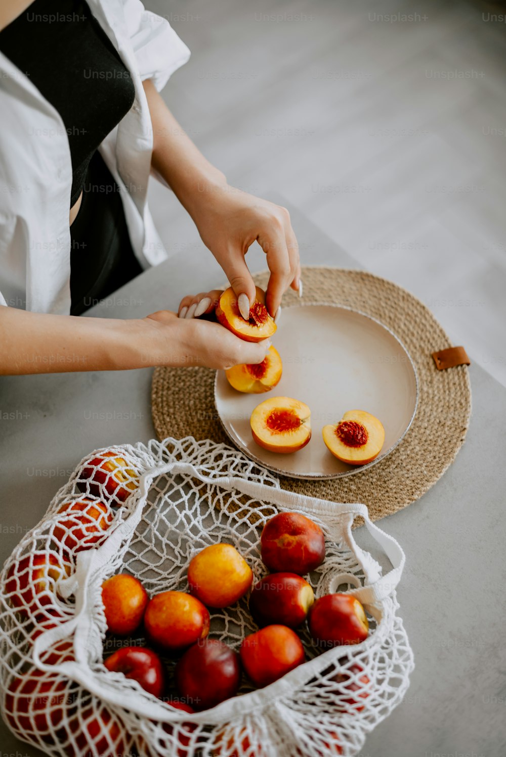 a woman is peeling peaches on a plate