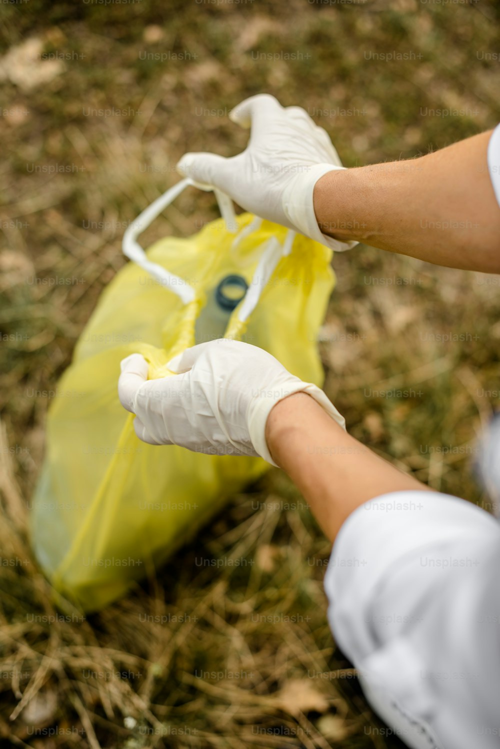 a person in white gloves holding a yellow bag