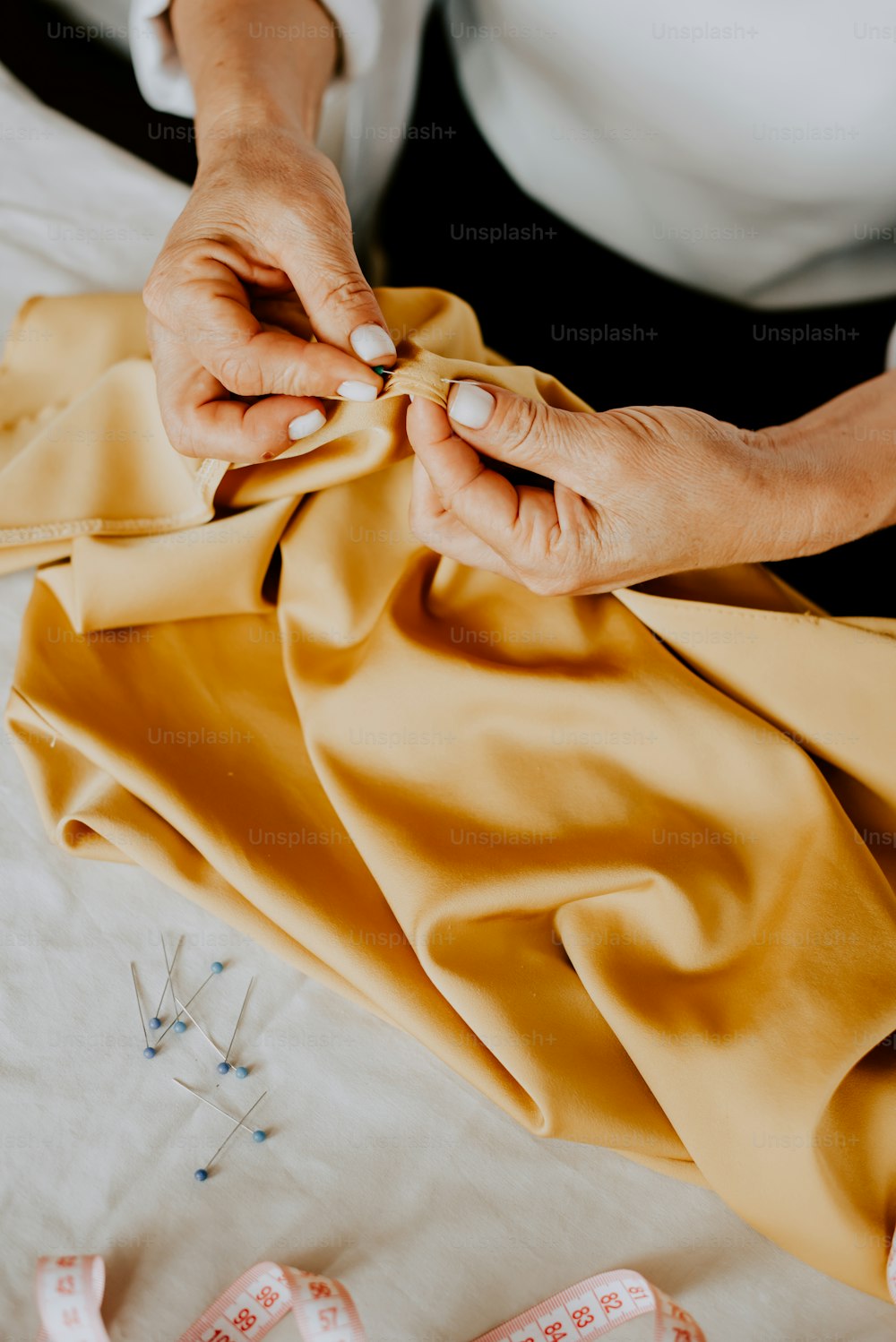 uma mulher está costurando um pano amarelo em uma máquina de costura