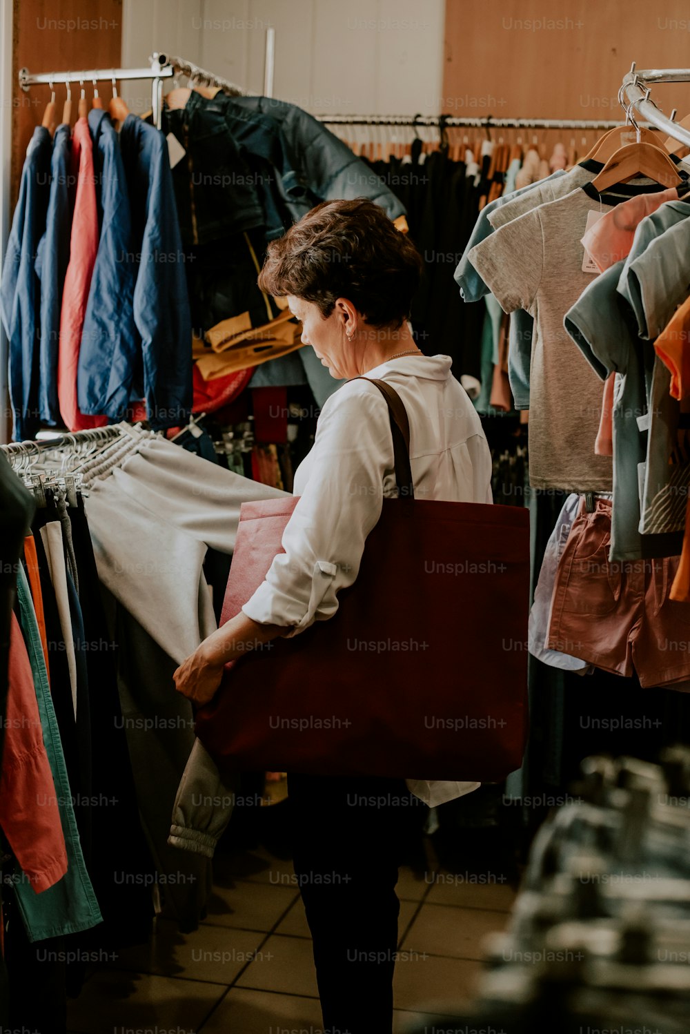 uma mulher carregando um saco vermelho em uma loja de roupas